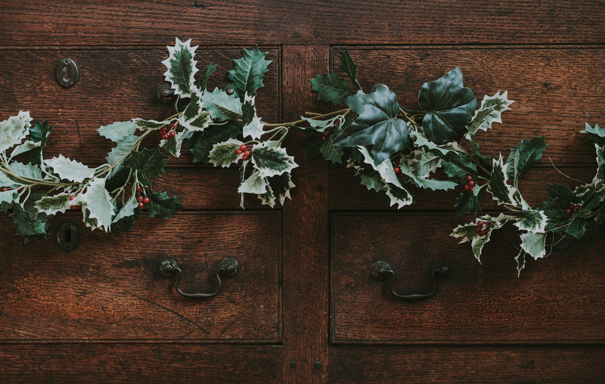 A holly garland draped over old wooden furniture at Christmas