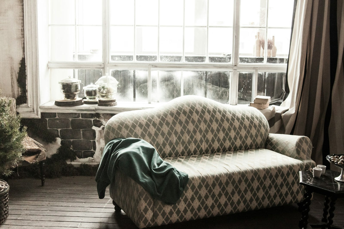A green wool throw over a sofa by a sunny window