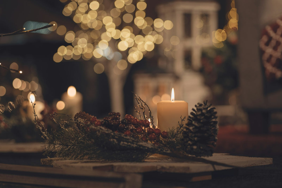Lit candles on a table with pine cones