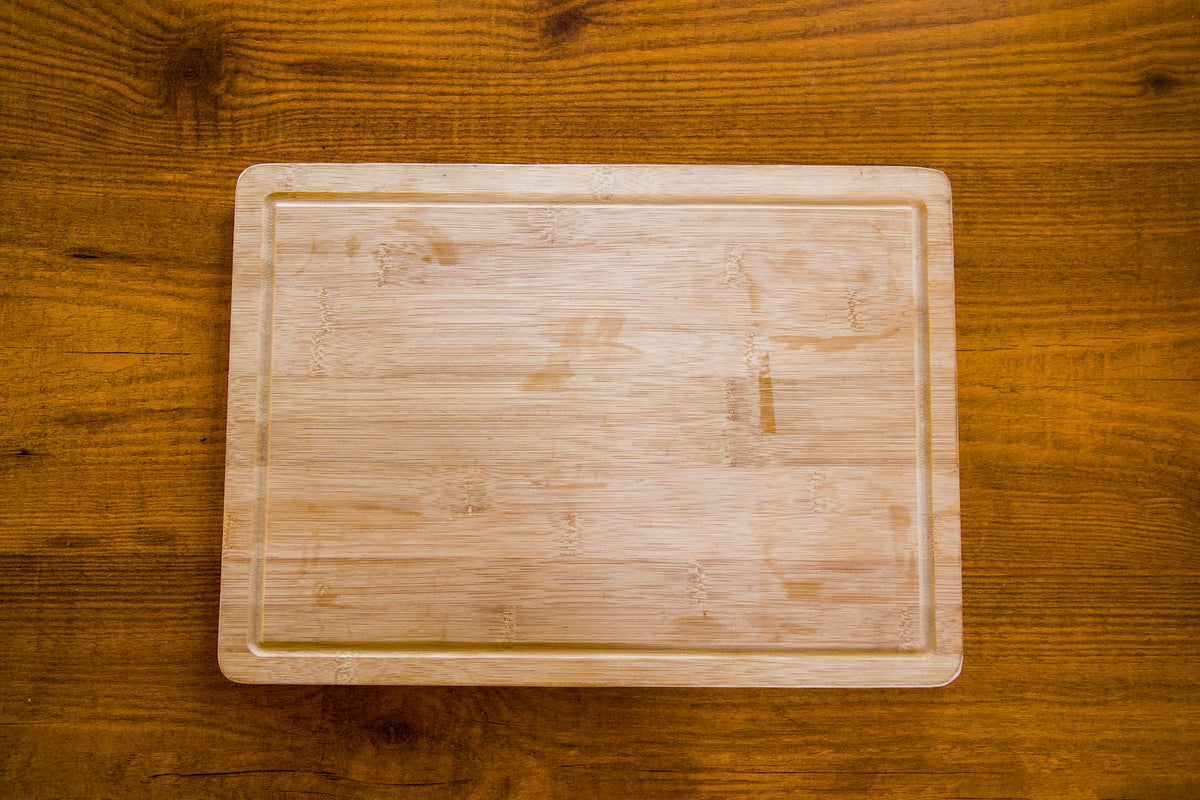 A new wooden chopping board on a wooden kitchen table