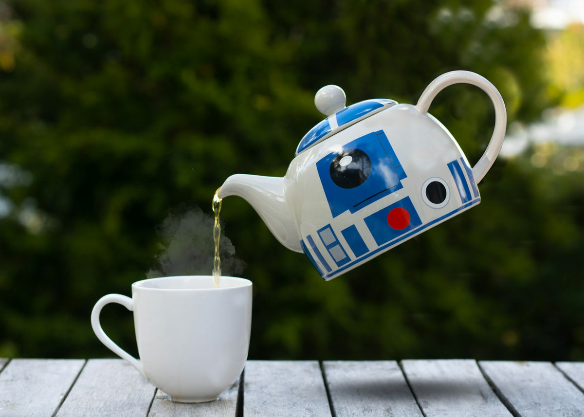 Tea being poured from a china teapot into a cup