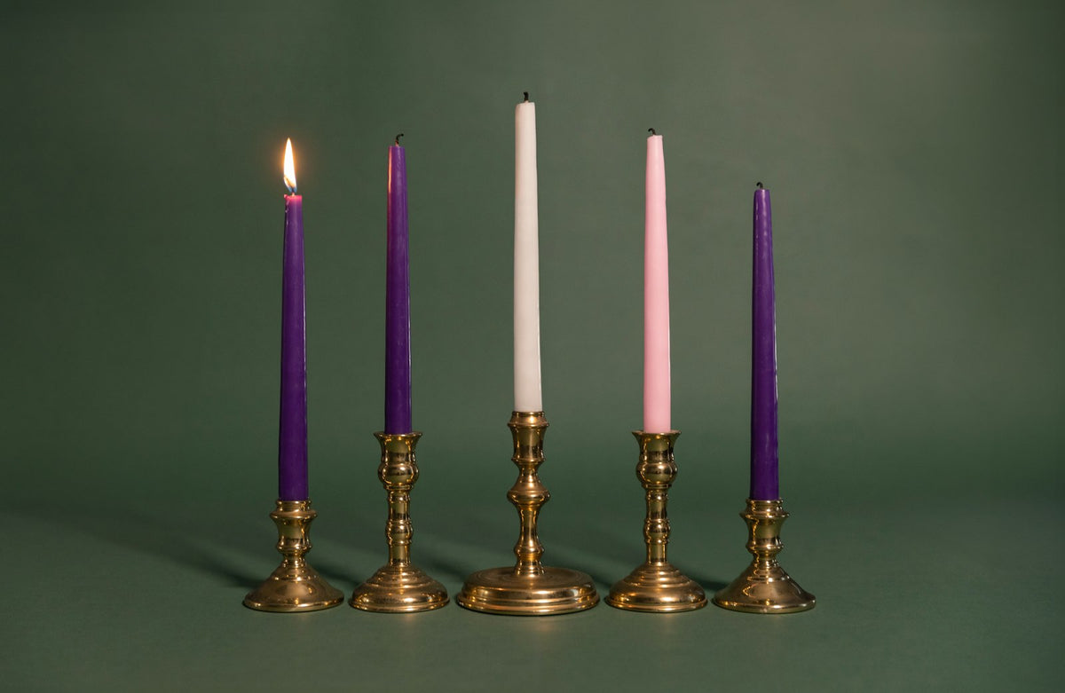 A row of candles in brass candle holders