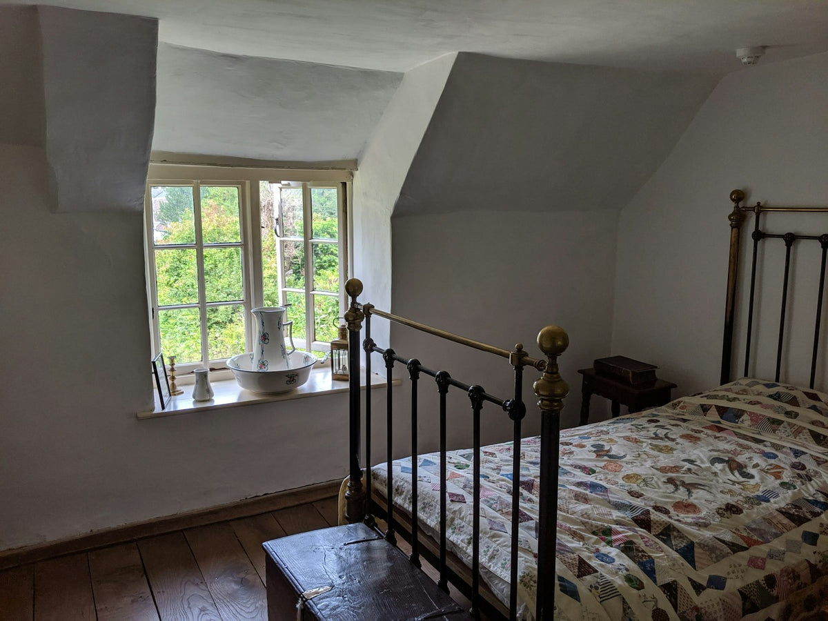 Sunlit cottage bedroom with an iron bed and patchwork quilt