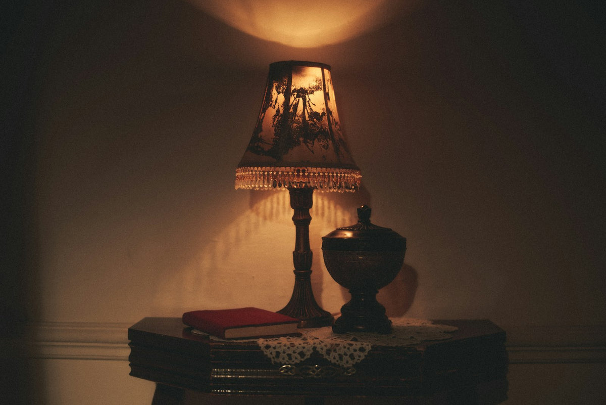 A table lamp beside its shade on a wooden desk