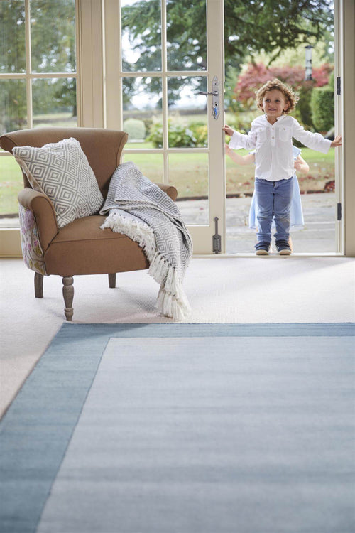Duck egg blue bordered wool rug in a room