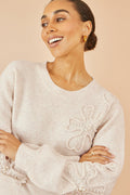Oatmeal knitted jumper with floral appliqué and pearl detailing, worn