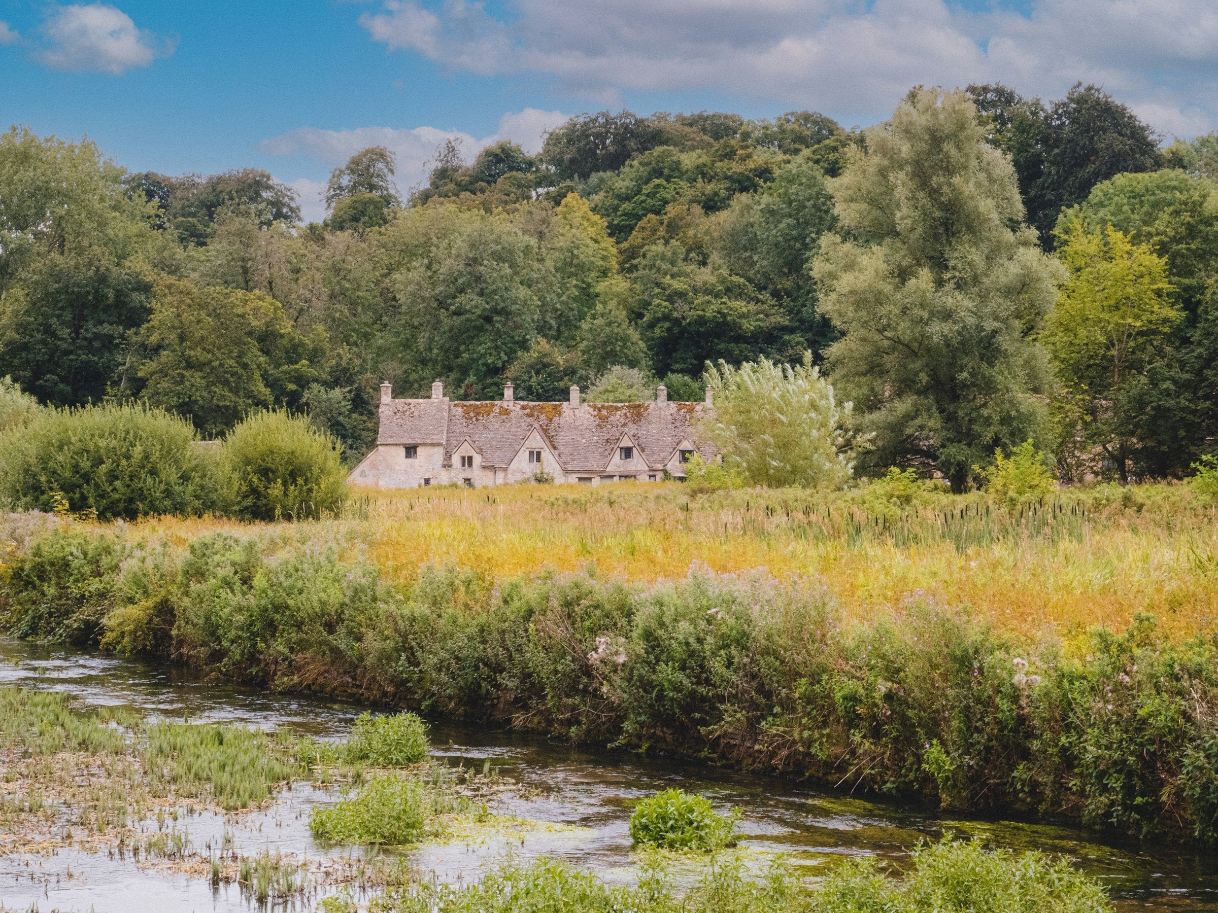 Honey-stone cottages beside a river in autumn