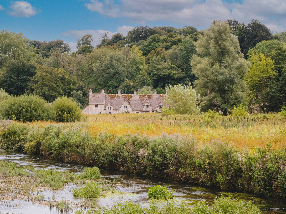 Honey-stone cottages beside a river in autumn