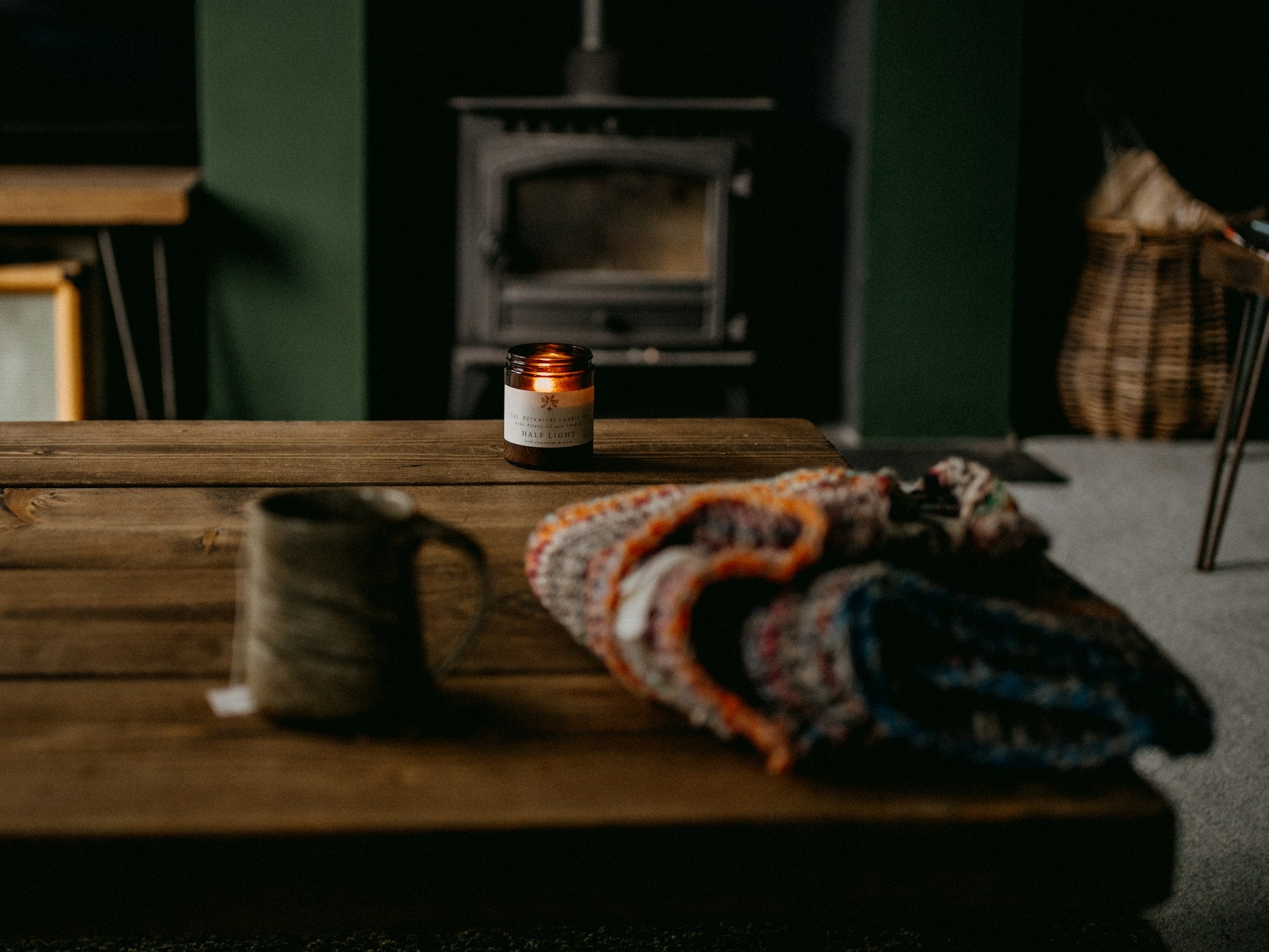 A blanket and a lit candle on a wooden table