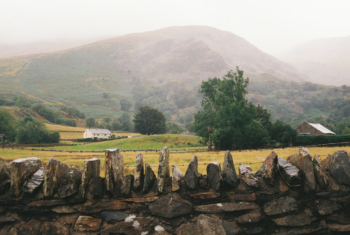 A dry stone wall in a misty green valley